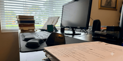 Mark Reynolds' writing desk with a marked-up manuscript for What Christians Do, books, keyboard, and computer, illustrating the writing process behind the book.