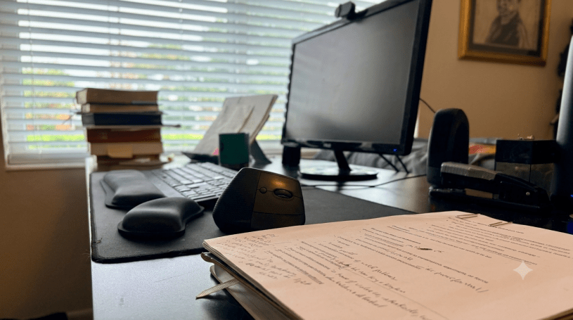 Mark Reynolds' writing desk with a marked-up manuscript for What Christians Do, books, keyboard, and computer, illustrating the writing process behind the book.