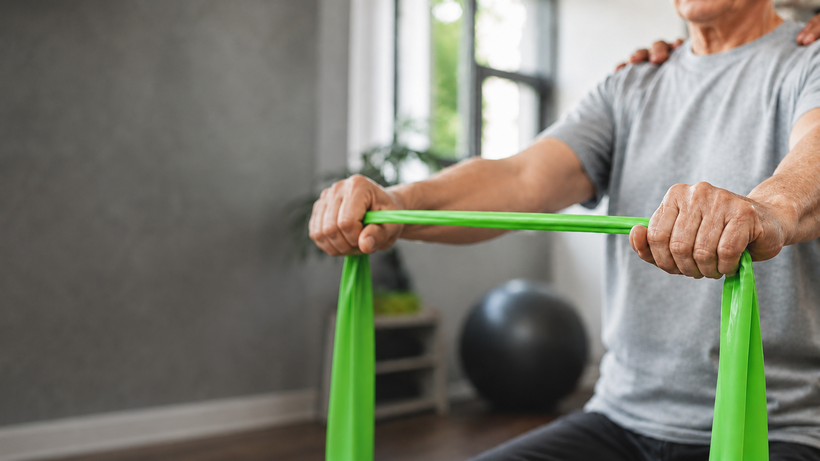 Older adult using a green resistance band during physical therapy.